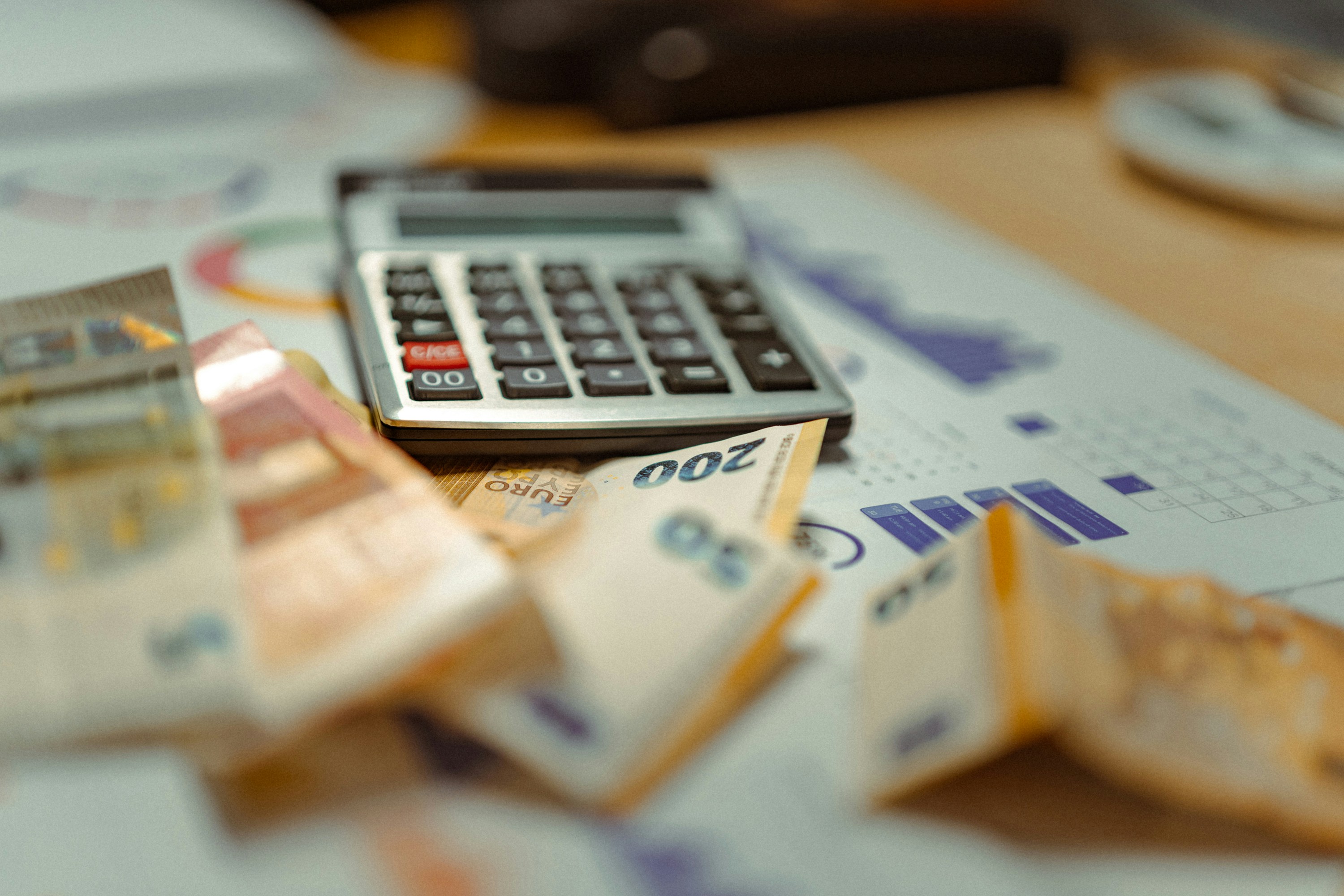 Calculating cost savings with precision: A desk adorned with currency, financial charts, and a calculator.
